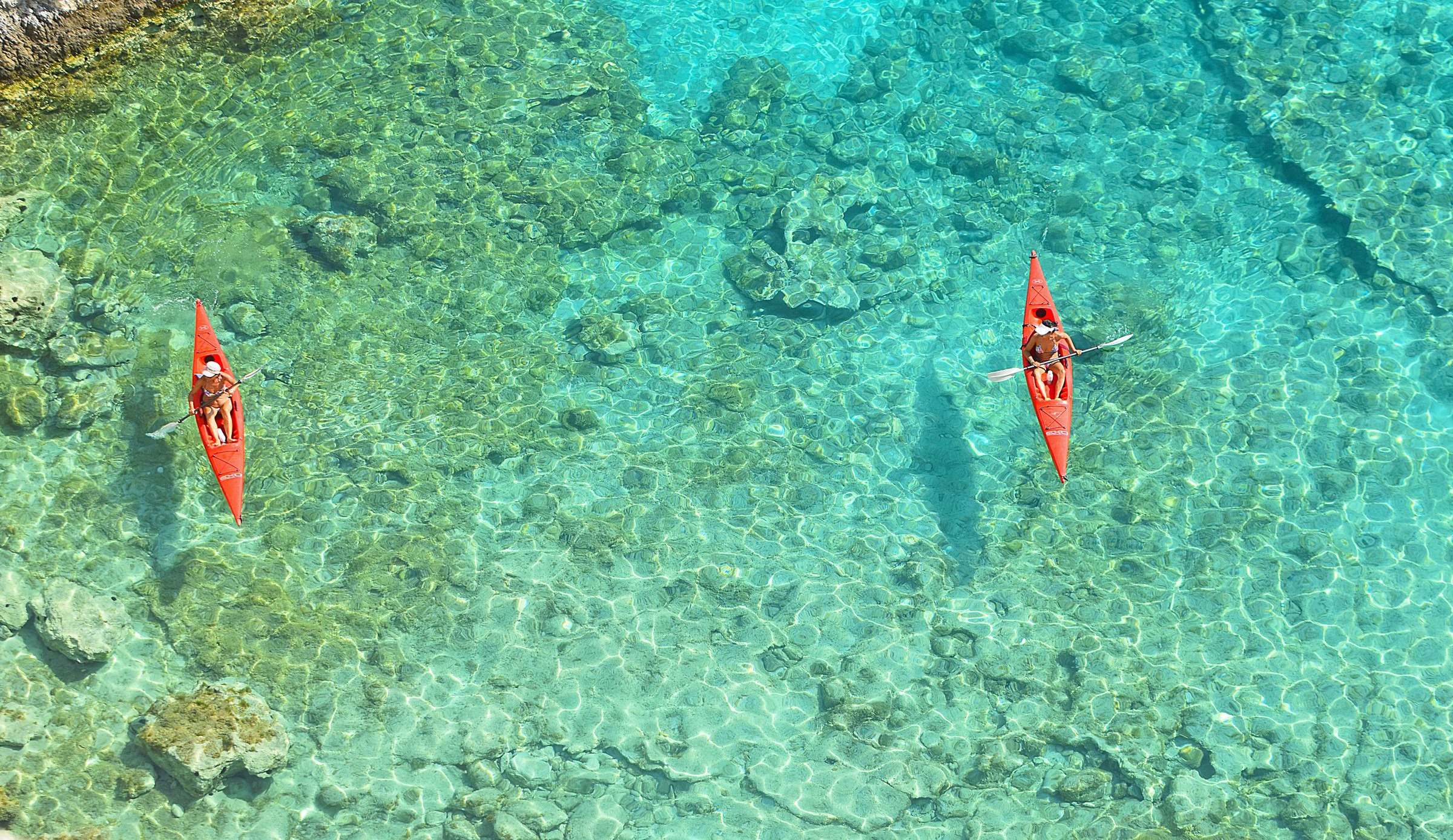 Two kayaks on crystal-clear turquoise water seen from above